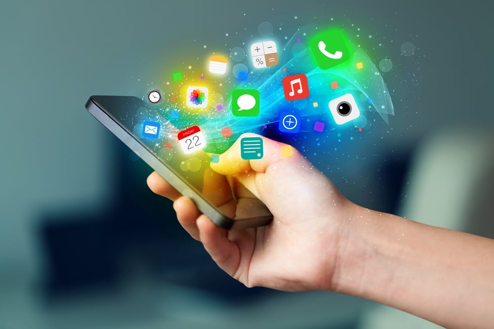 Hand holding a smartphone with colorful app icons popping out of the phone